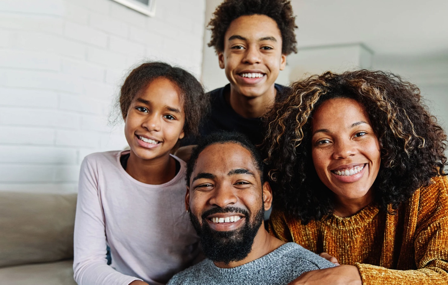 A family of four smiling together at home